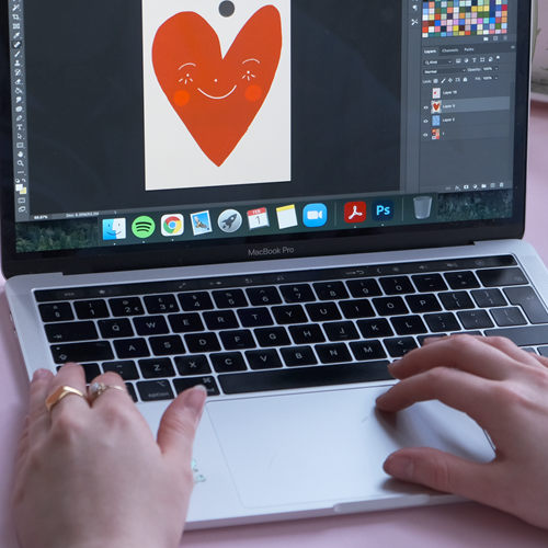 Editing design on computer of red heart with smiling face