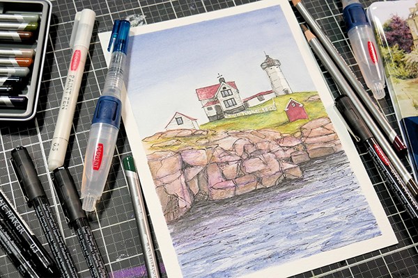 Seaside painting surrounded by Derwent Graphitint pencils