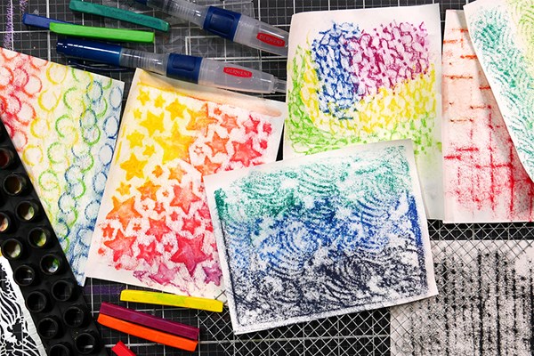 Various textured designs on paper next to Derwent Inktense blocks